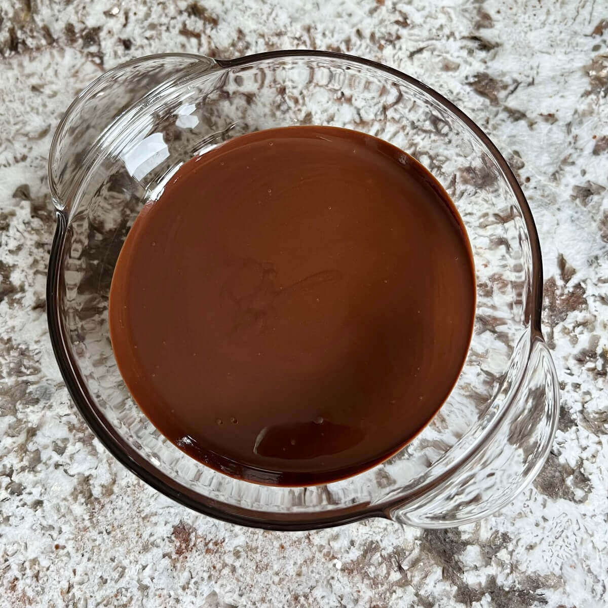 A mixture of tahini and melted chocolate in a glass bowl.