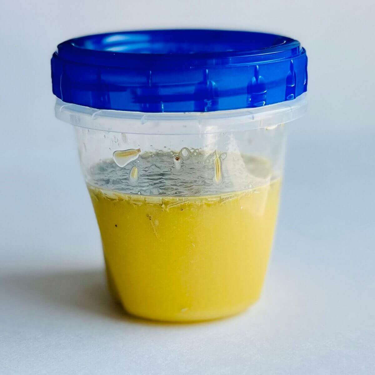 Rosemary dressing in a clear plastic container with a blue lid.