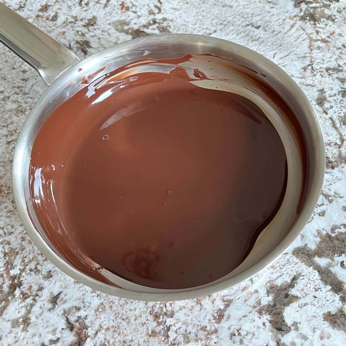 Melted chocolate in a stainless steel pan.
