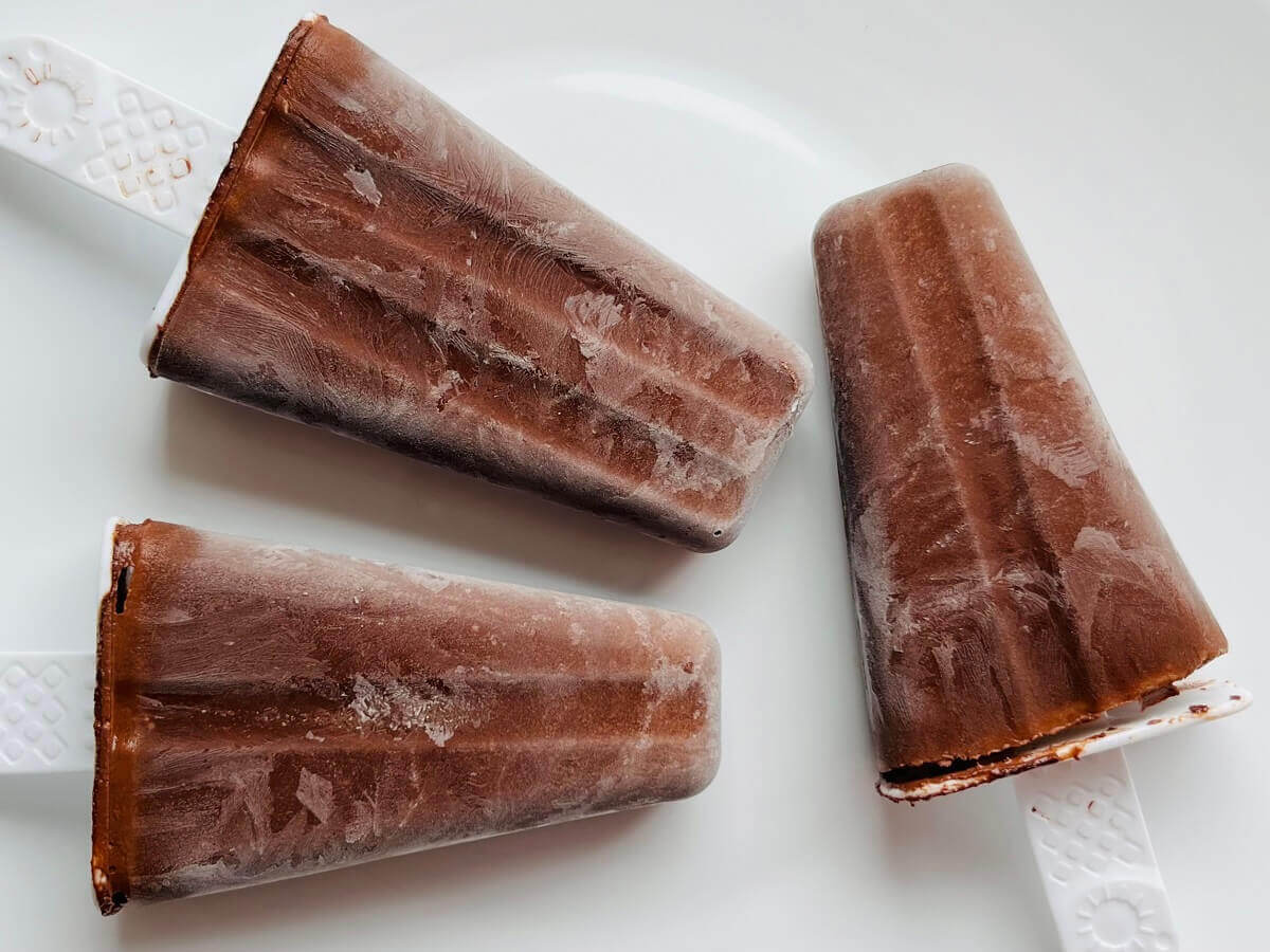 Three popsicles on a white plate.