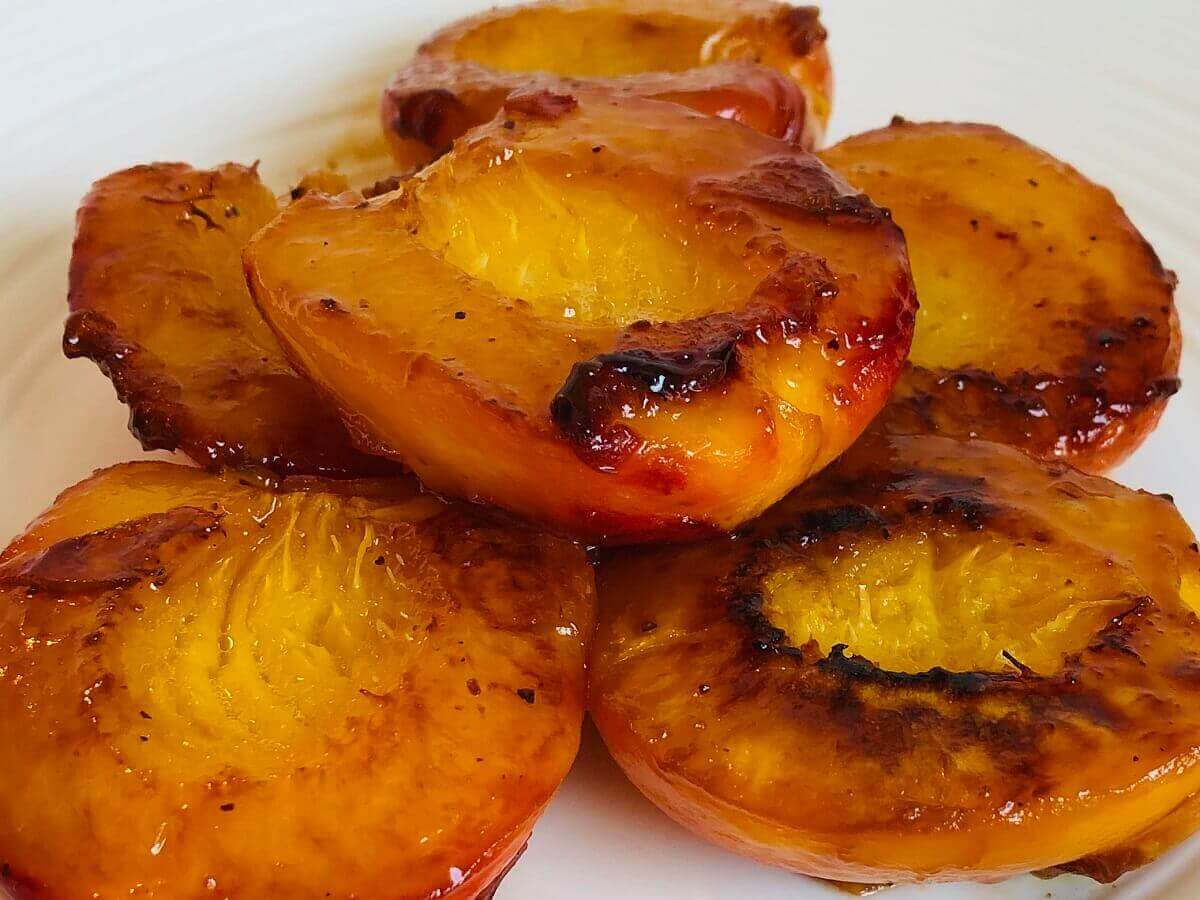 Sauteed peaches piled on a white plate.