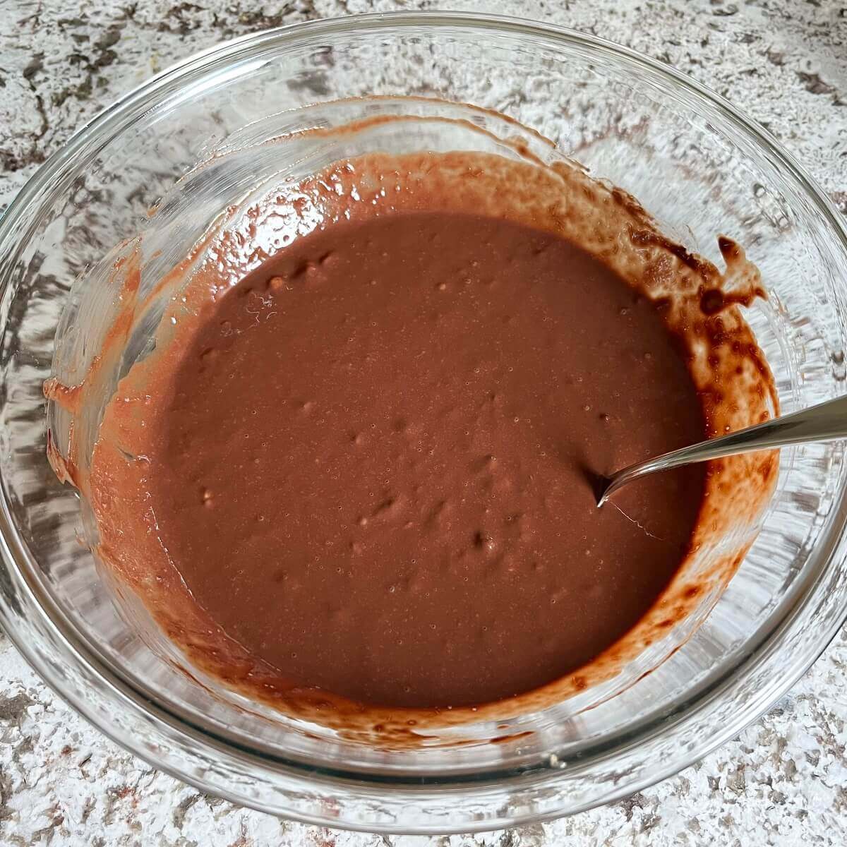 Wet ingredients for brownie batter in a glass mixing bowl.