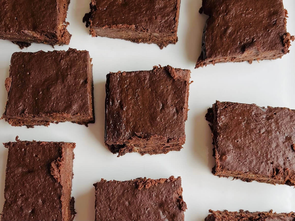 Brownies cut in squares on a white plate.