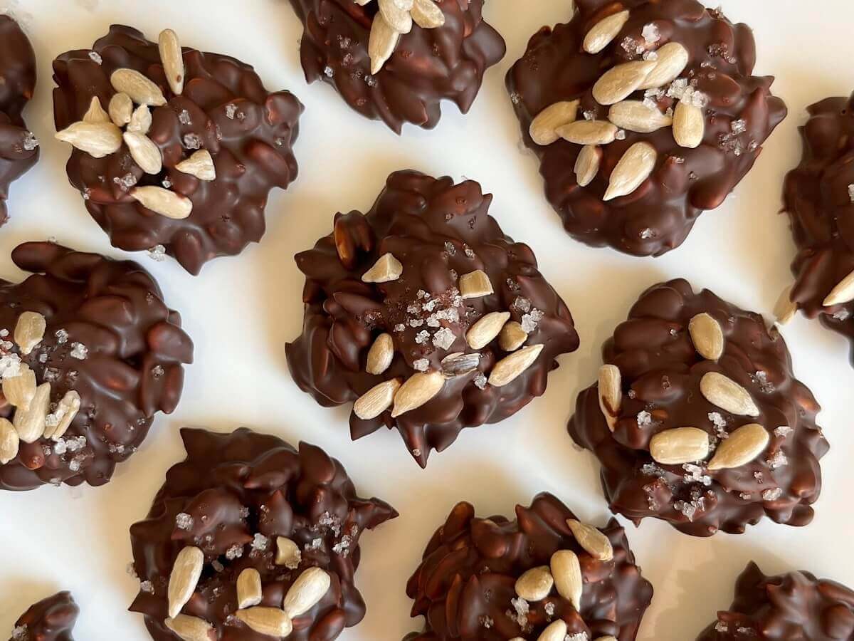 Chocolate sunflower seed clusters on a white plate.