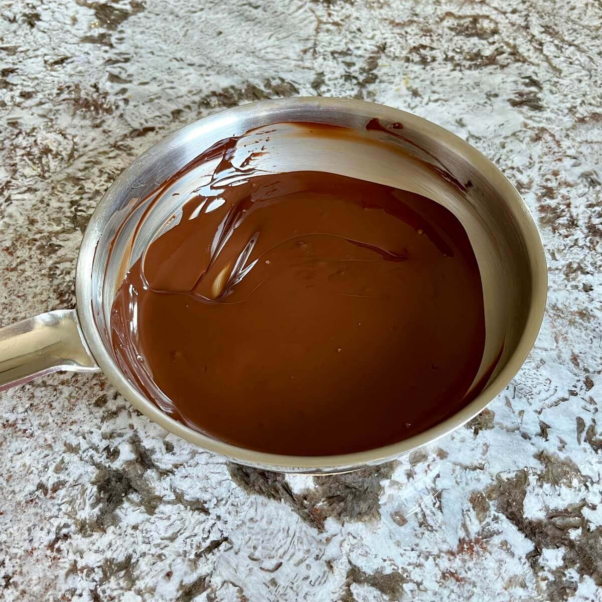 Melted dark chocolate in a steel pan.