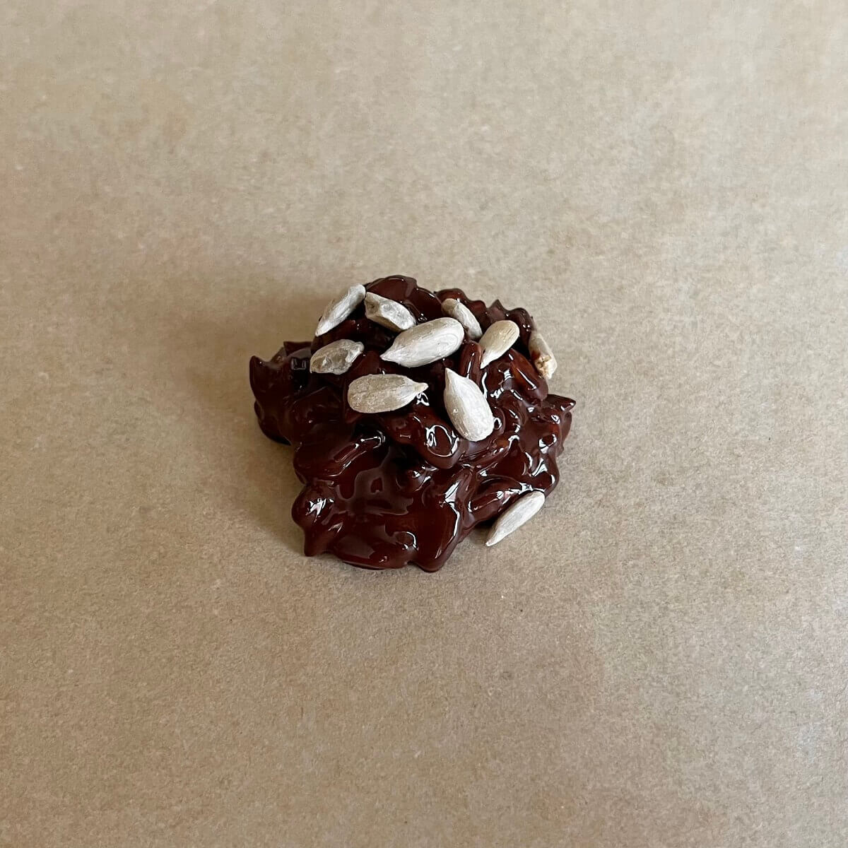 A cluster of sunflower seeds and dark chocolate on a sheet pan lined with parchment paper.