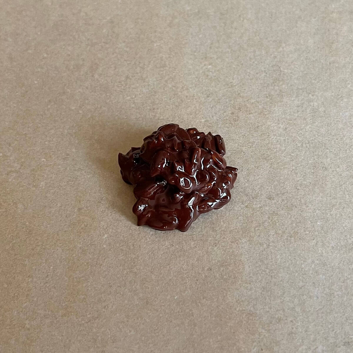 A small pile of sunflower seeds coated in melted dark chocolate on a sheet pan lined with parchment paper.