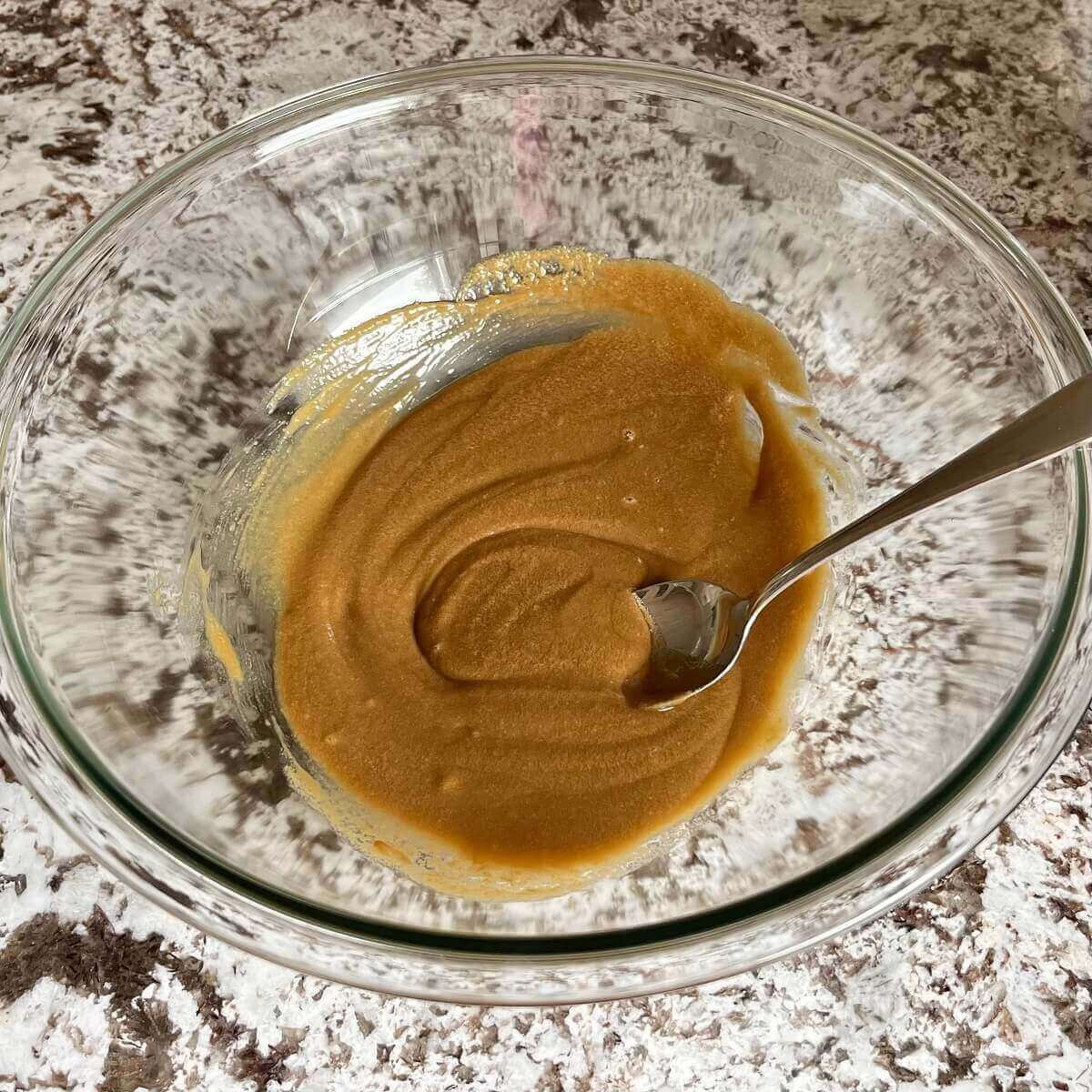 Wet ingredients for cookie dough in a glass mixing bowl.